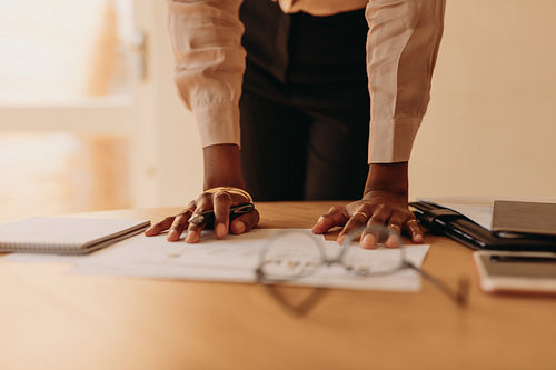 Businesswoman reading documents with hands resting on the table.
