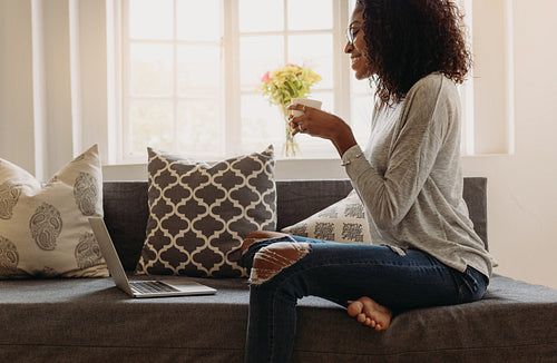 Woman enjoying a cup of coffee while working on laptop