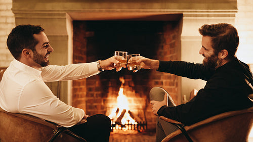 Cheerful male friends celebrating with whiskey glasses
