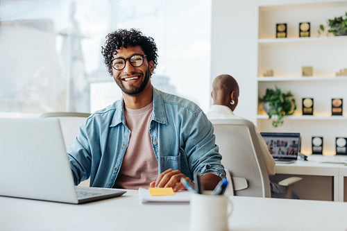 Successful young entrepreneur working happily on his laptop in a modern office