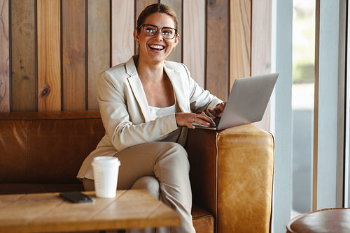Happy business woman sitting in a cafe and using a laptop