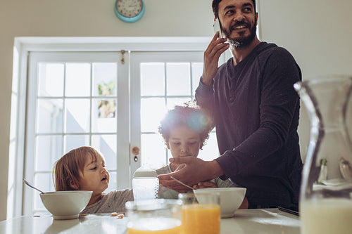 Man talking over mobile phone standing at the breakfast table