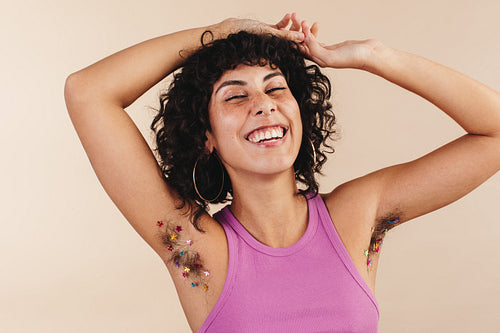Happy young woman flaunting her confetti-decorated arm pits