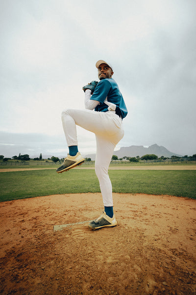 Professional baseball player in pitching stance on the field with blue uniform and gloves