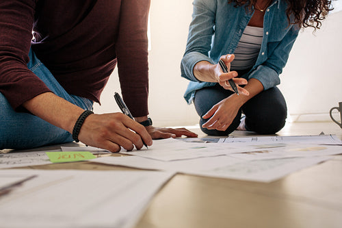 Business colleagues sitting on the floor and discussing work with business papers spread on the floor