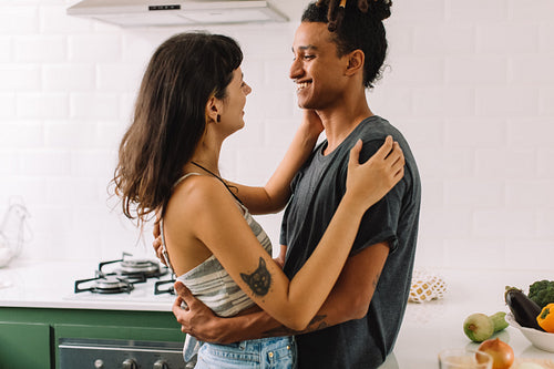 Affectionate young couple smiling at each other in the kitchen