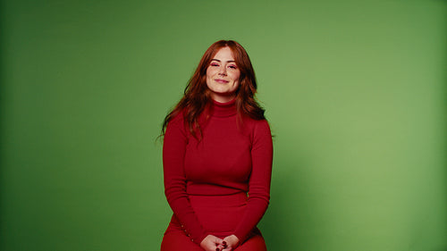 Happy young woman with long red hair laughing and smiling on green screen
