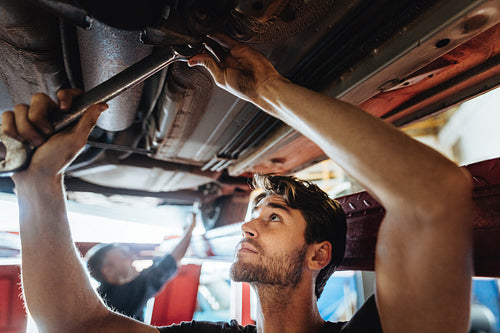 Auto mechanic working underneath a lifted car