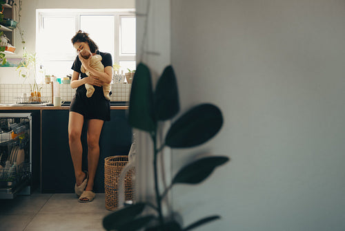 Mother holds baby in kitchen at home