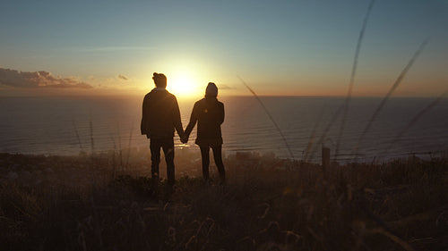 Loving couple on mountain peak at sunset