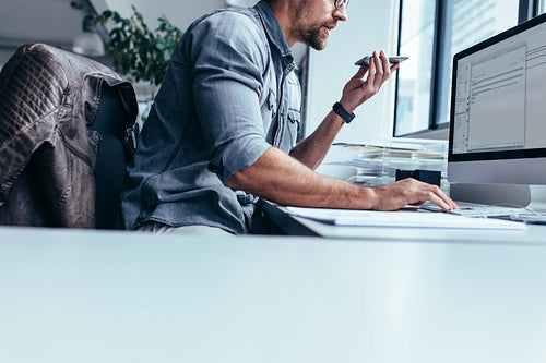 Young businessman talking on mobile phone and using computer