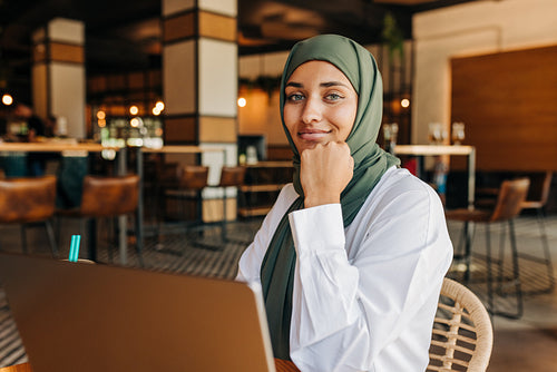 Beautiful Muslim woman working with a laptop in a cafe