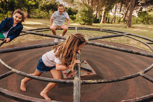 Children playing in a park on a rustic merry-go-round