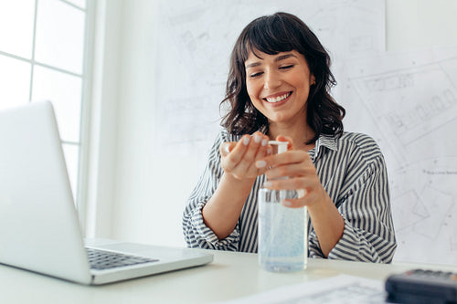 Female architect sanitising her hands with sanitizer