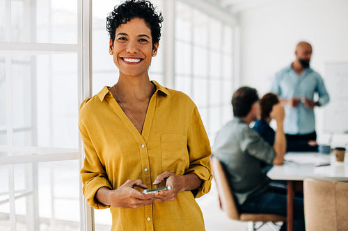 Business woman smiling at the camera and holding a cellphone