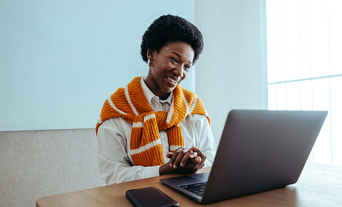 Confident woman with afro hairstyle engaged in a virtual meeting using a laptop
