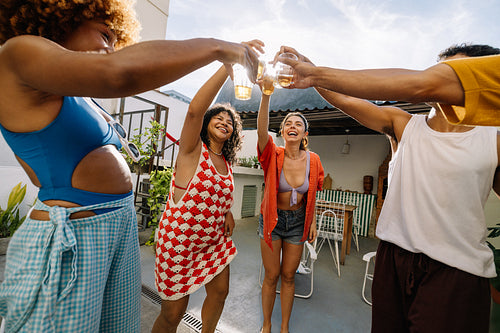 Group of friends toasting drinks on a sunny outdoor patio