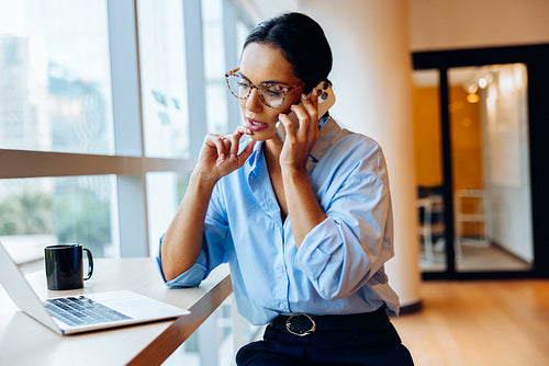 Professional woman multitasking on phone while working at a desk