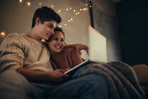 Couple sitting in cozy living room with a laptop
