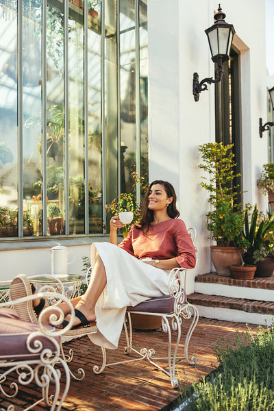 Smiling young woman having coffee outside a hotel