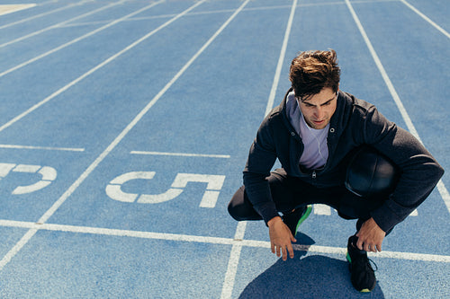 Athlete sitting on the running track with a medicine ball