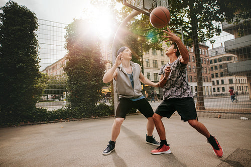Two young men playing a game of basketball