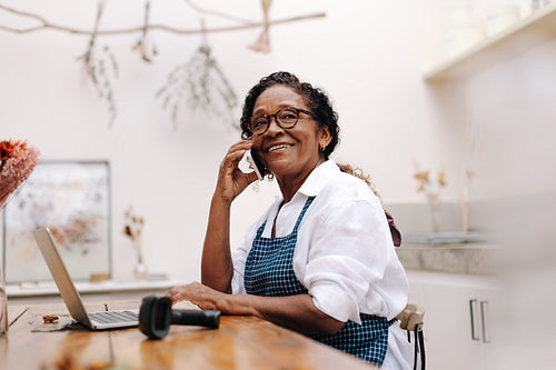 Happy flower store owner talking with her clients on a phone call