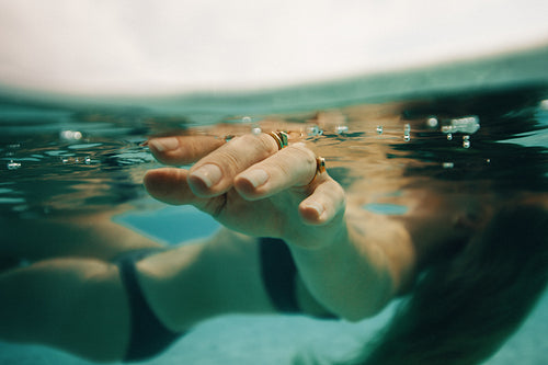 Close-up of a hand submerged underwater wearing rings with serene bubbles