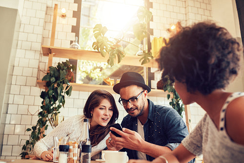 Young couple looking at smart phone while sitting in cafe