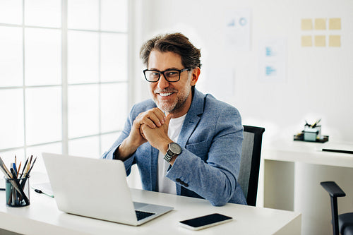 Mature business man smiling at the camera while sitting at his desk