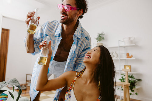 Friends celebrate at home party with beer bottles