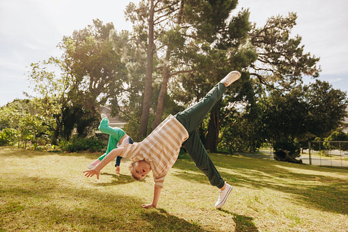 Children practicing cartwheels in a lush green park under sunny skies