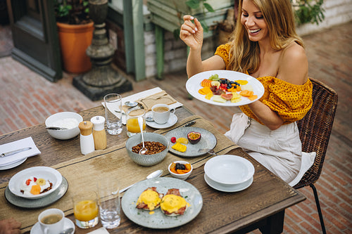 Cheerful woman enjoying a healthy breakfast at a luxury hotel