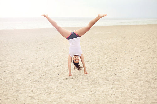 Cheerful Woman on the Beach Doing Handstand
