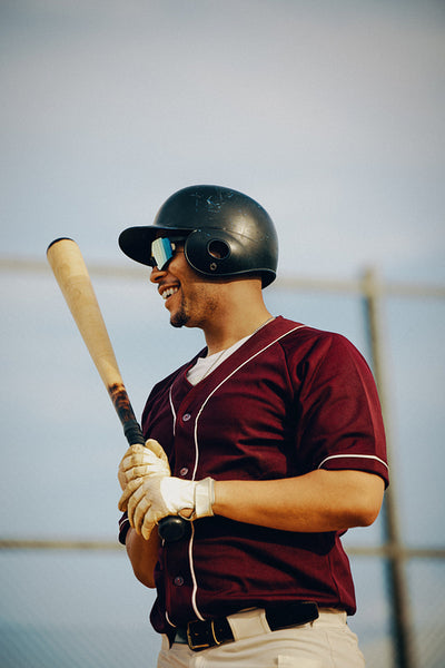 Cheerful amateur baseball player in burgundy jersey ready to bat in a local league game