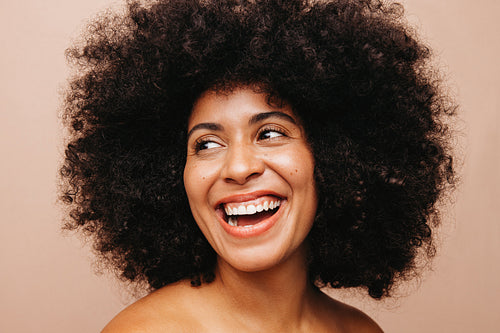 Gorgeous woman with an Afro hairstyle smiling happily in a studio
