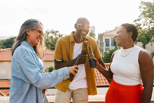 Diverse friends cheering with drinks outdoors, celebrating a joyful moment together