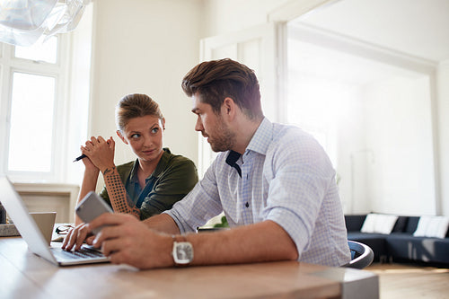 Young couple sitting together at home with laptop
