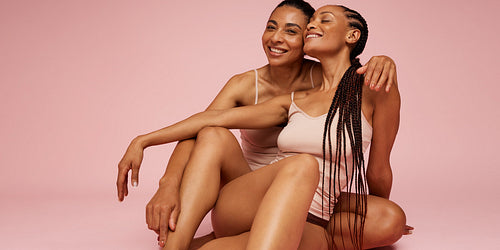 Cheerful women sitting on floor in underwear
