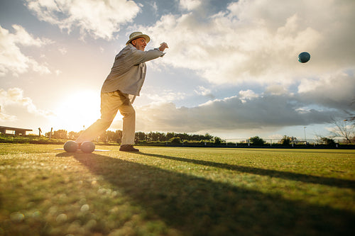 Senior man playing boules in a lawn