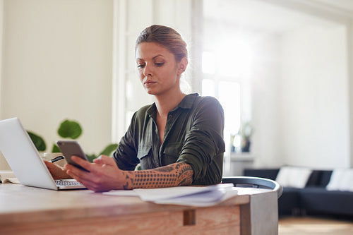 Young woman using mobile phone at home office