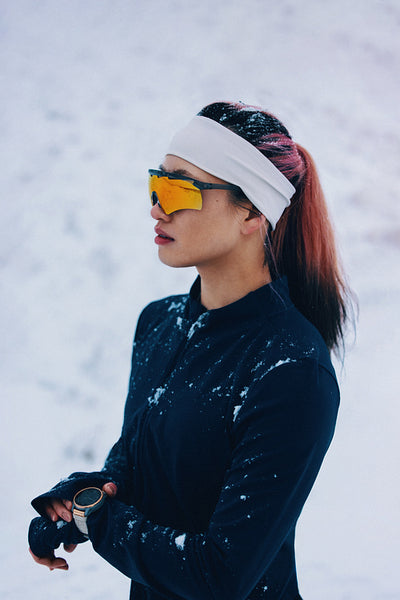 Winter sports athlete posing outdoors in snow with sunglasses and headband