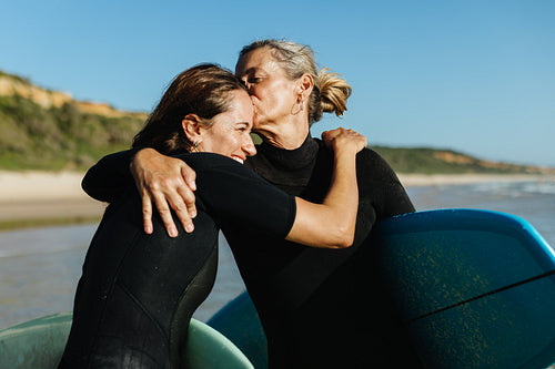 Mother and daughter sharing a warm moment while surfing on vacation
