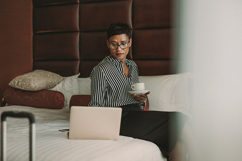 Businesswoman in hotel room with laptop and coffee