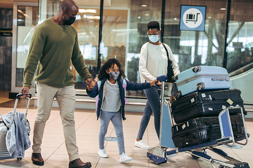 African family of three walking with luggage at airport