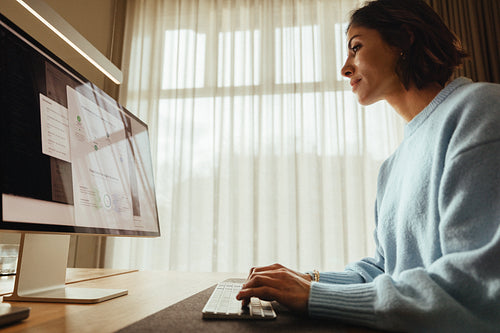Woman works at computer desk in office with focused attention