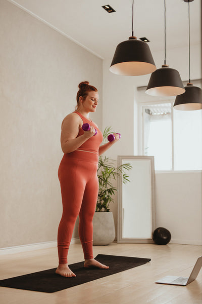 Woman exercising with dumbbells watching fitness video