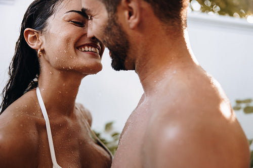Happy young couple kissing under an outdoor shower