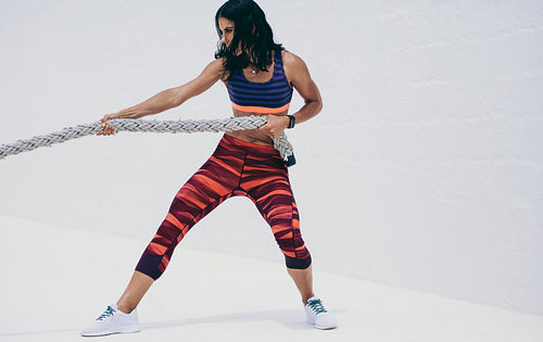 Woman in fitness wear pulling a battle rope