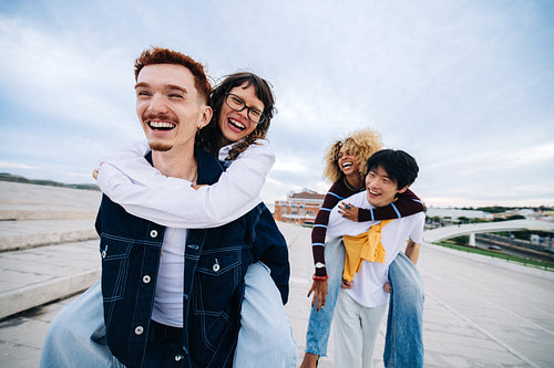 Young friends laughing on piggyback rides outdoors